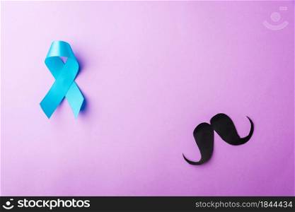Black mustache paper and light blue ribbon, studio shot isolated on purple background, Prostate cancer awareness month, Fathers day, minimal November moustache concept