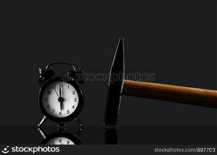 Black old style alarm clock isolated. wake up with a hammer on a black background. wake up with a hammer on a black background. Black old style alarm clock isolated