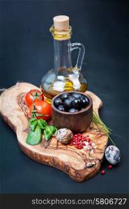 Black olives with bottle of oil on a wooden table