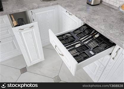 black open drawer with silver cutlery in modern white kitchen. drawer with silver cutlery in modern white kitchen
