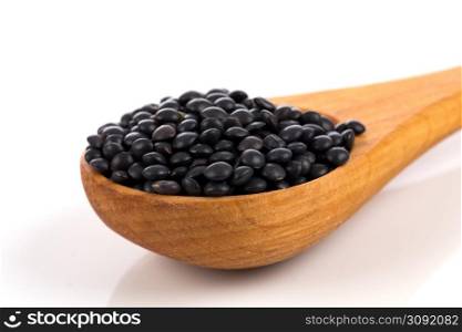 Black organic lentils in wooden spoon isolated on white background