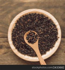black organic rice grain spoon bowl wooden backdrop