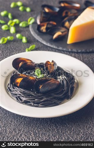 Black pasta with mussels and parmesan on the white plate