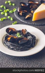 Black pasta with mussels and parmesan on the white plate