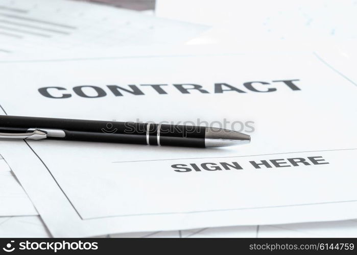 Black pen on a contract with a sign here area