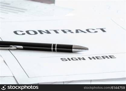 Black pen on a contract with a sign here area