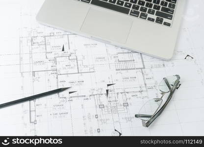 black pencil and computer laptop on architectural drawing paper for construction