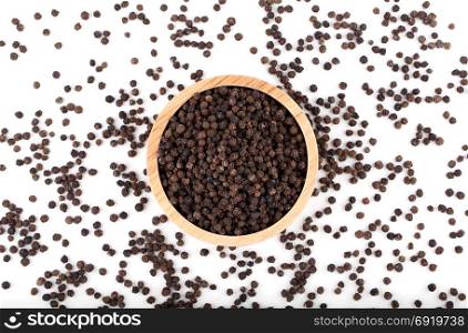 black peppercorns in wooden bowl on white background