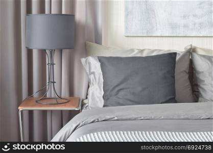 Black pillow on bed and black shade lamp on bedside table