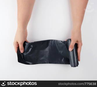 black plastic garbage bag in female hands on a white background, top view