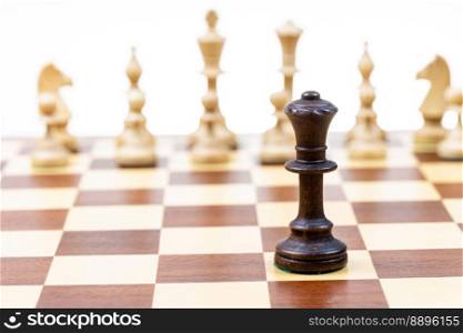 black queen against white chessπeces in background on wooden chessboard close up  focus on queen 