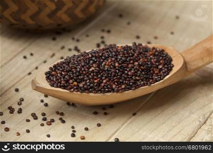 Black quinoa on a wooden spoon