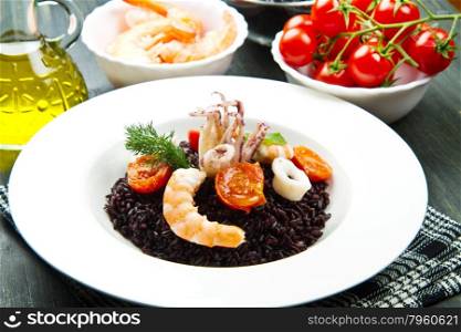 Black rice with sliced squids ,prawns and tomato on white plate