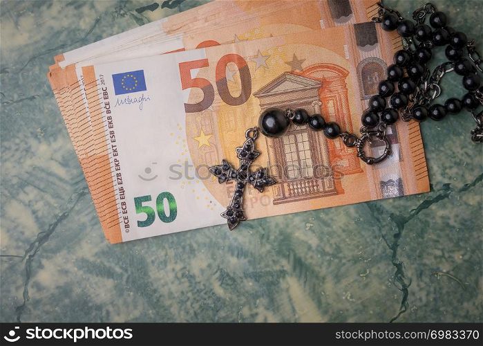 Black rosary and euro money on green table,concept photo.