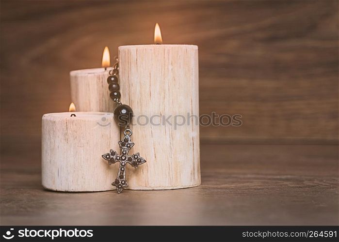 Black rosary on the Candle at wooden table,religion concept,vintage style.