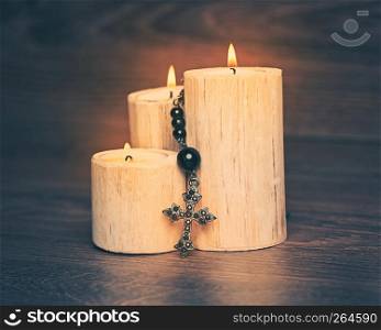 Black rosary on the Candle at wooden table,religion concept,vintage style with split toning.