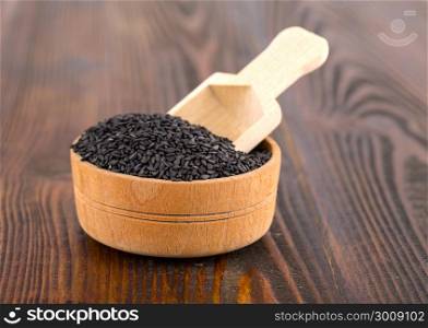 black sesame in a Cup and spoon on wooden surface
