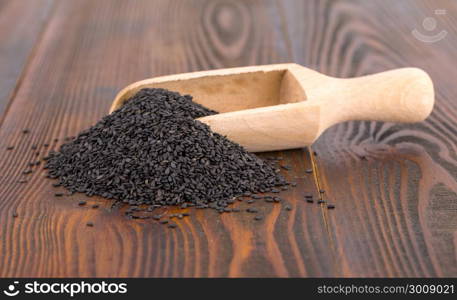 black sesame in spoon on wooden surface