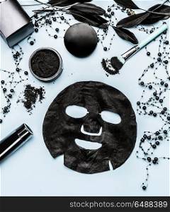 Black sheet mask and cosmetic products setting with Activated Charcoal, top view. Beauty and modern skin care concept. Branding mock up