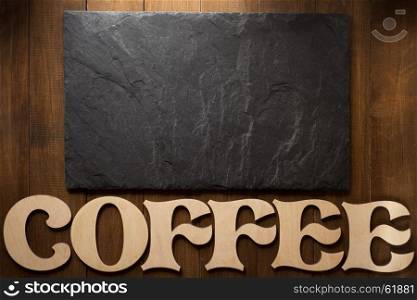black slate stone and coffee letters on wooden background