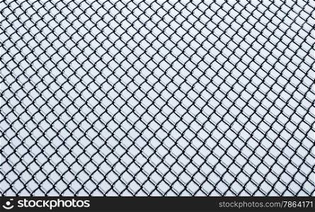 Black small chain-link fence covered in ice on white background.
