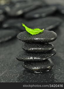 Black spa pebbles with rain drops on dark background