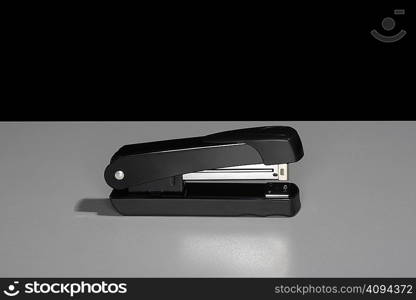 Black stapler sitting on a table.