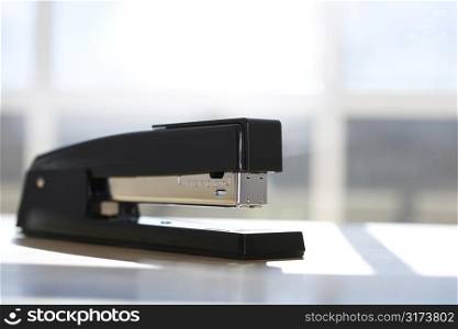 Black stapler with window in background.
