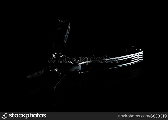 black steel folding multitool on dark background, low-key