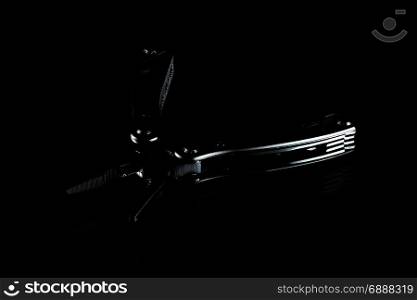 black steel folding multitool on dark background, low-key
