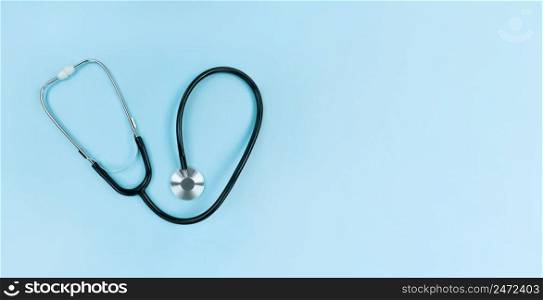 Black stethoscope on a soft blue background. Simple flat lay with copy space.. Black stethoscope on soft blue background. Simple flat lay with copy space.