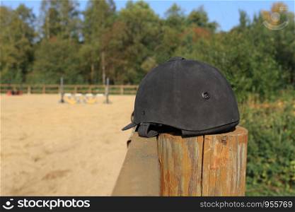 black suede jockey helmet in the foreground on the fence still life