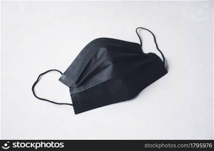 Black surgical face mask with ear strap on white background
