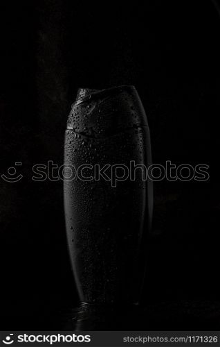 black sweaty plastic bottle for shampoo or shower gel on black isolated background