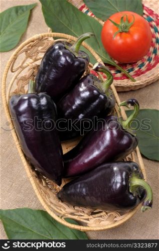 Black sweet pepper in a basket with tomato