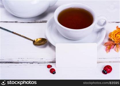 black tea in a round white cup with a saucer on a white wooden background and an empty paper tag