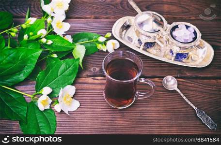 Black tea in a Turkish glass cup on a brown table, top view