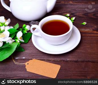 black tea in a white cup with a saucer on a brown wooden table
