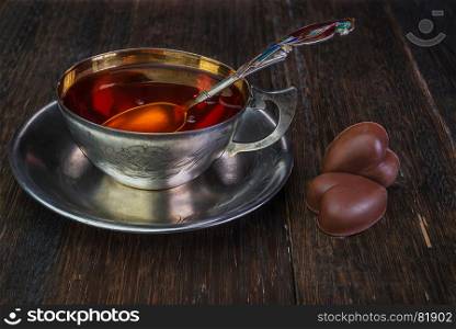 Black tea in vintage silver cup on an old wooden background
