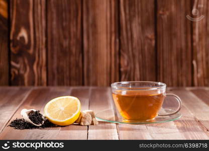 Black tea with lemon and brown sugar cubes on the wooden table, place for text. Various types of tea