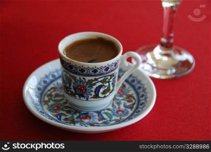 Black turkish cofee and glass water on a red cloth
