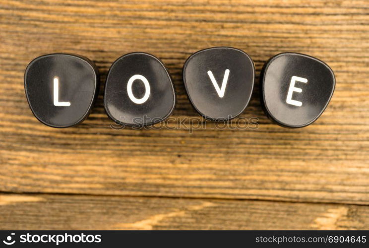 Black typewriter keys laying on wood table say the word love