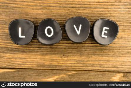 Black typewriter keys laying on wood table say the word love