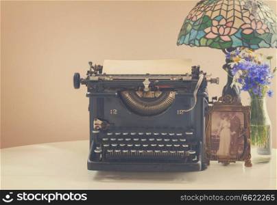 black vintage typewriter with books and lamp, retro toned. typewriter on table