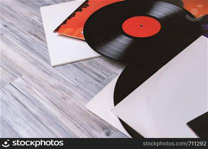 Black vinyl record and covers album on the background of their gray wooden boards.Vintage style with copy space.