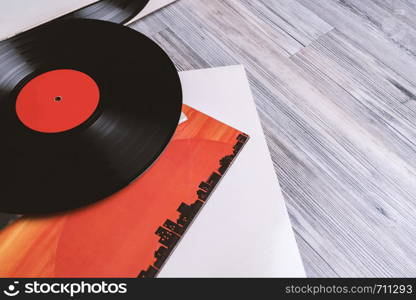 Black vinyl record and covers album on the background of their gray wooden boards.Vintage style with copy space.