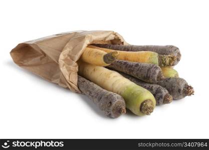 Black, white and yellow carrots in a paper bag on white background