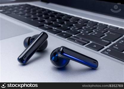 Black wireless headphones over laptop on table background