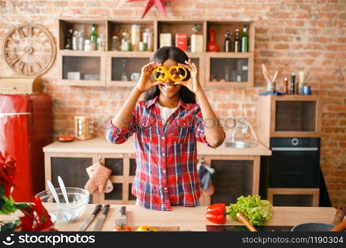 Black woman having fun on the kitchen. African female person preparing vegetable salad at home. Healthy lifestyle