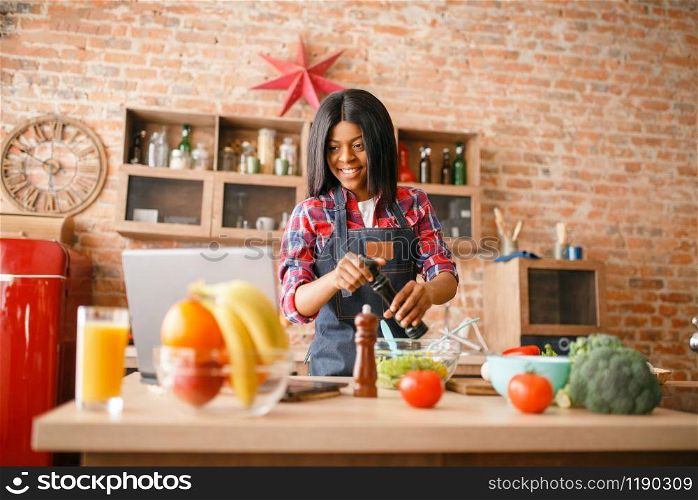 Black woman in apron cooking healthy breakfast on the kitchen. African female person preparing vegetable salad at home. Black woman in apron cooking healthy breakfast
